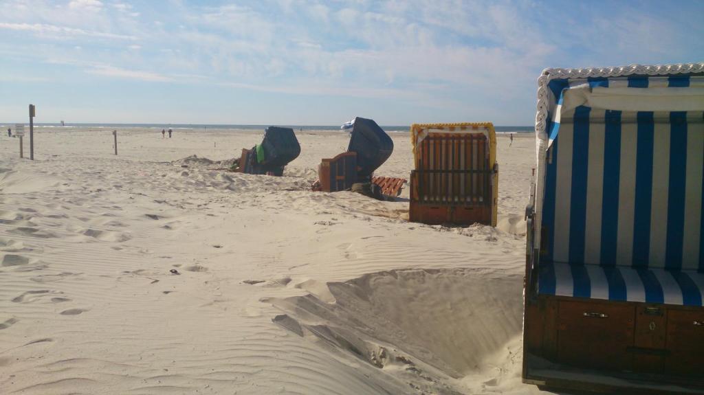 a row of beach chairs in the sand on the beach at Strandhotel Juister Hof in Juist