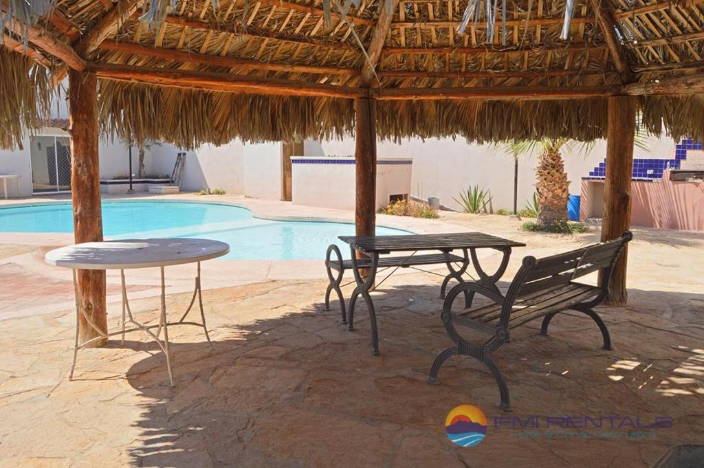 una mesa y un banco bajo una sombrilla de paja en Abel's Villa by FMI Rentals, en Puerto Peñasco