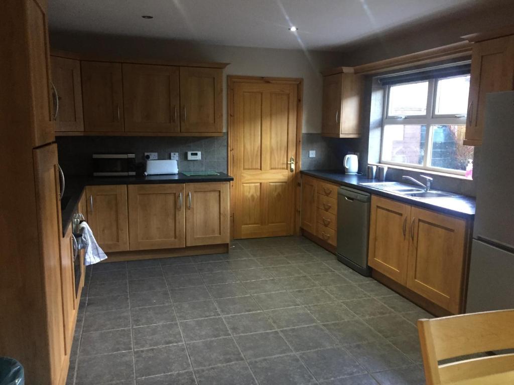 an empty kitchen with wooden cabinets and a window at Glendona Lodge in Glenavy