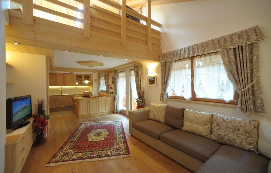 ヴァル・ディ・ゾルドにあるRomantic Chalet Dolomitiの広いリビングルーム(ソファ付)、キッチンが備わります。