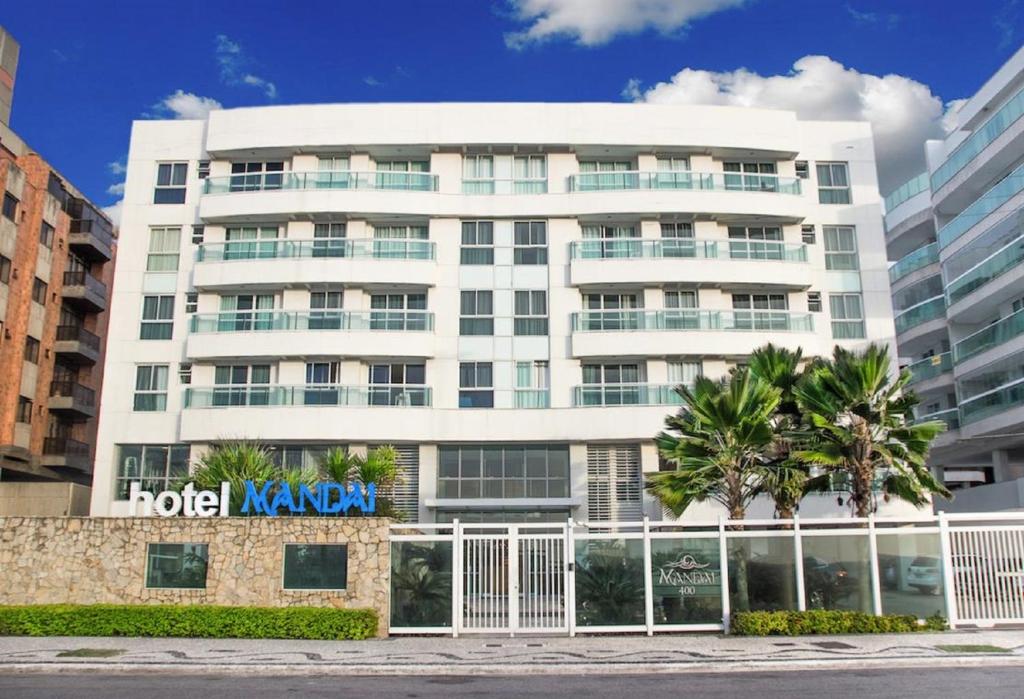 un edificio navano hotel con palmeras delante en Apartamento Pé na Areia 212 - Apartamento Beira Mar 210 - Cabo Frio en Cabo Frío