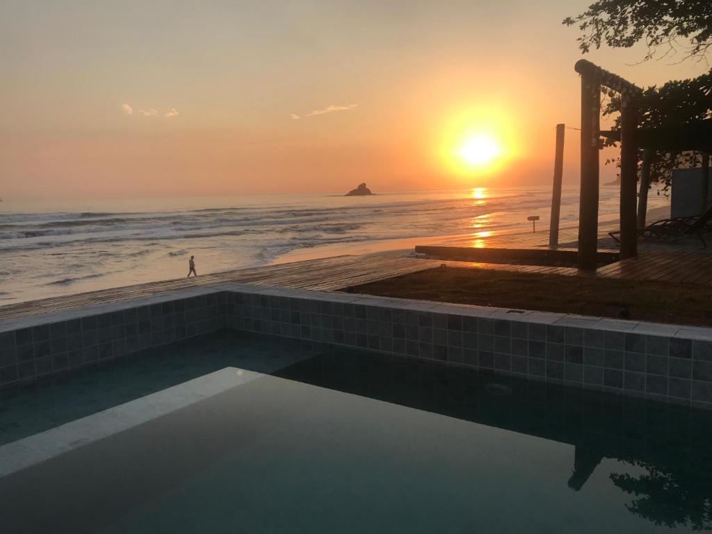 a sunset over the ocean with a swimming pool at Casatua Pousada in Juquei