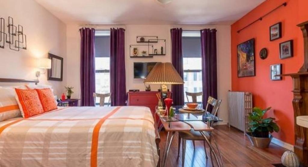 ニューヨークにあるFabulous Fully Furnished Studio Minutes From Times Square!のオレンジ色の壁のベッドルーム1室、ベッド1台、テーブルが備わります。