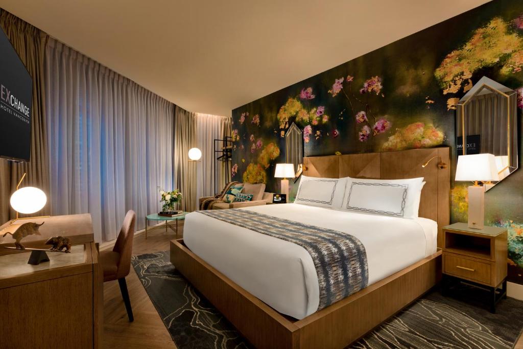 a bedroom with a large bed with a painting on the wall at EXchange Hotel Vancouver in Vancouver