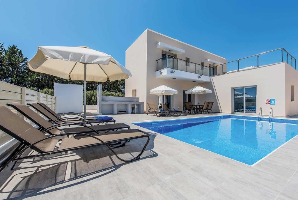 a villa with a swimming pool with chairs and an umbrella at Demitrios Vine in Coral Bay