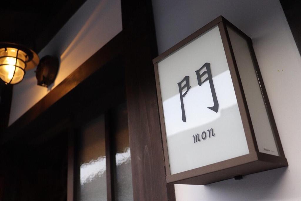 una señal en el lateral de un edificio con un reloj en 近江の町家 門, en Omihachiman