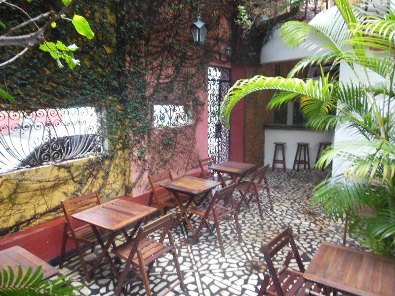 un grupo de mesas y sillas junto a una pared en Café Hostel Kebab Salvador en Salvador