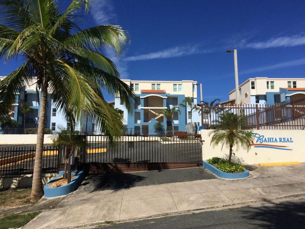 a fence with palm trees in front of a building at Sunset Paradise - Ocean View Penthouse Apartment in Cabo Rojo