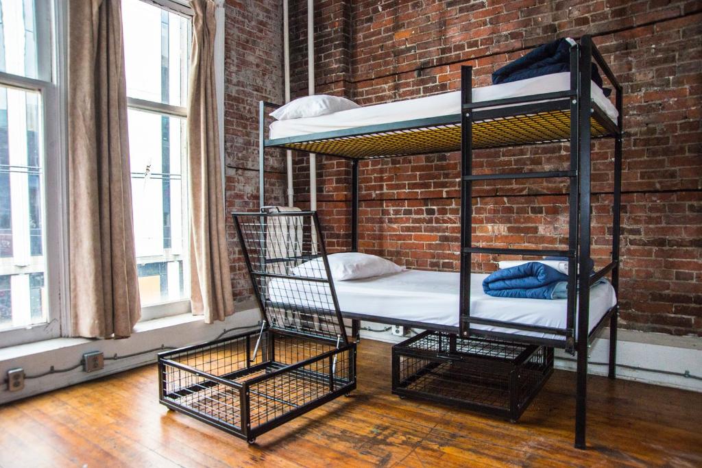 two bunk beds in a room with a brick wall at The Cambie Hostel Gastown in Vancouver