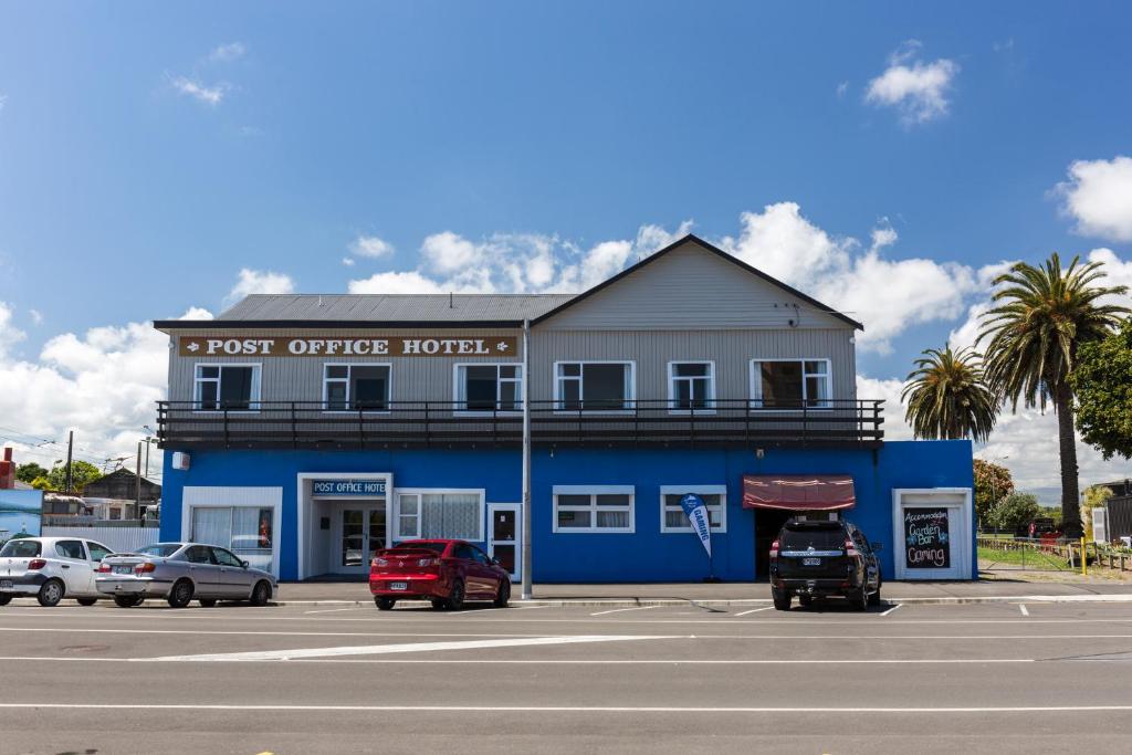 Foxton的住宿－郵局酒店，一座蓝色的建筑,前面有汽车停放