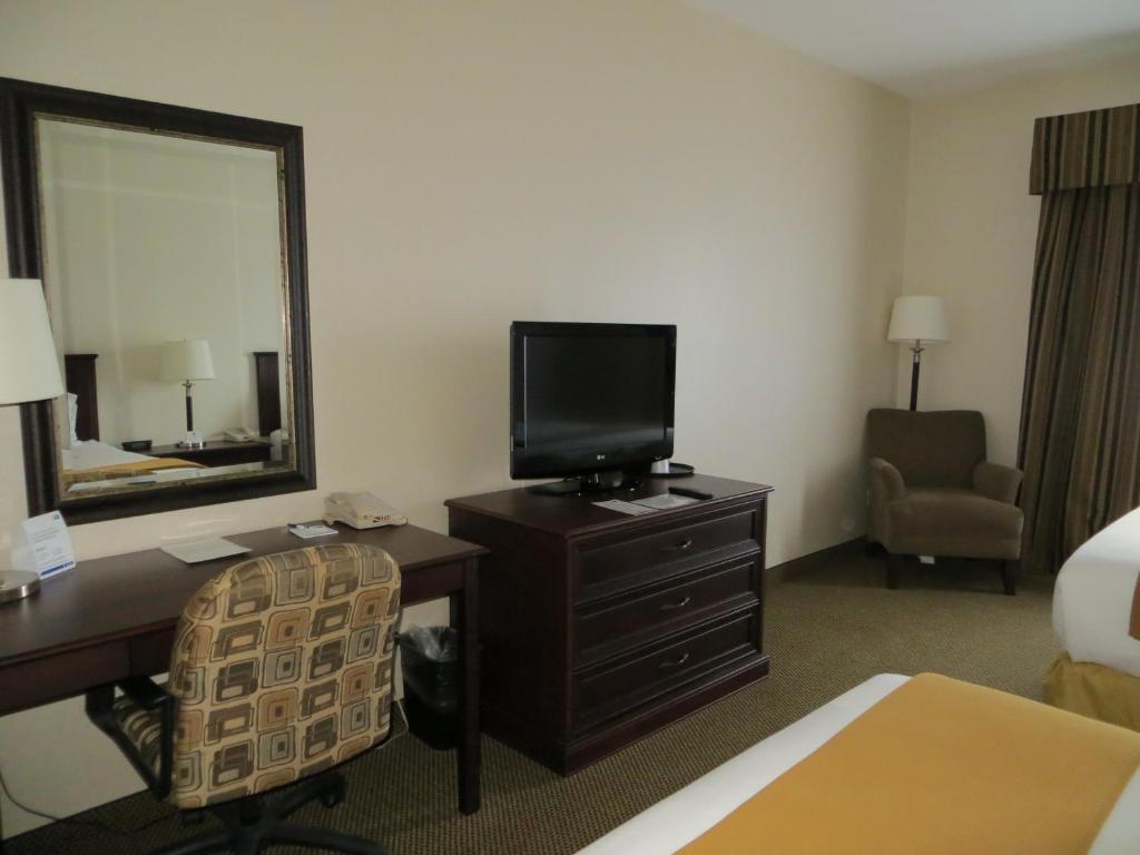a hotel room with a desk with a television and a mirror at Holiday Inn Express & Suites Whitecourt by IHG in Whitecourt