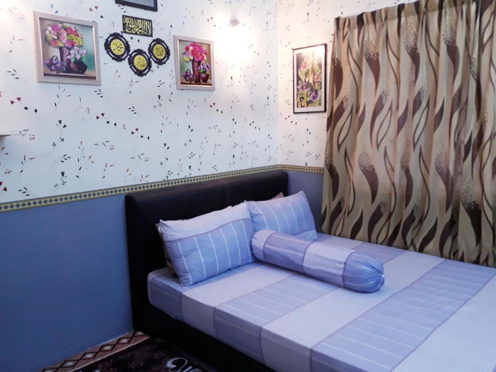 Cama en habitación con sofá azul en TSA Jitra Homestay, en Kampong Pantai Halban