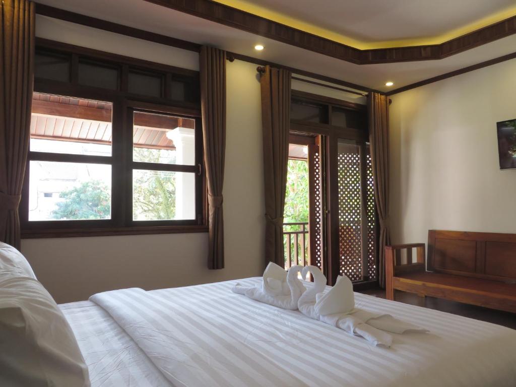 a bedroom with a white bed with towels on it at QUEEN'S HOUSE in Luang Prabang