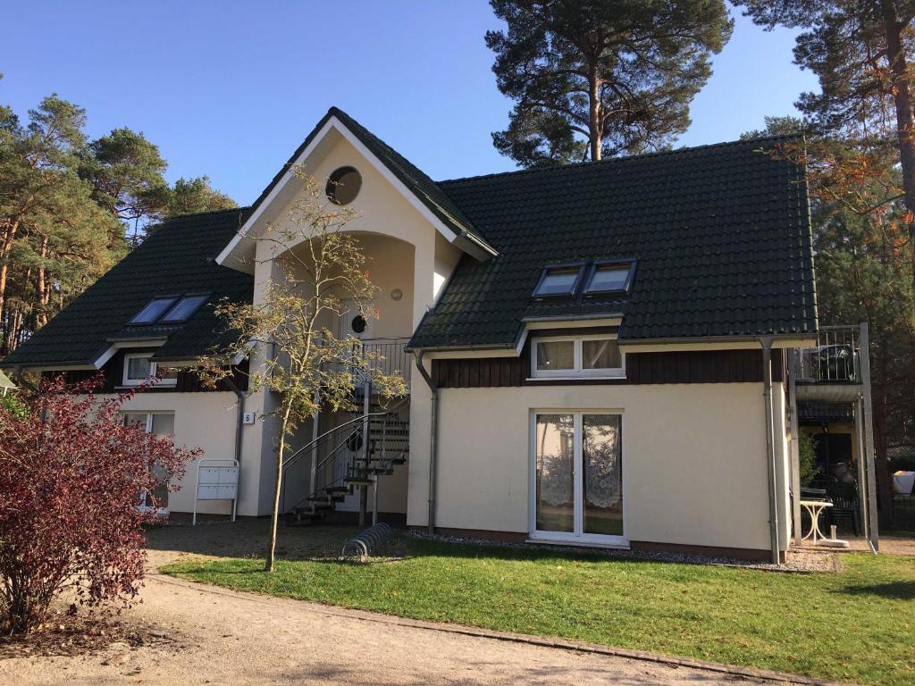 uma casa branca com um telhado preto em Ferienhaus Ostseestern KREF em Trassenheide