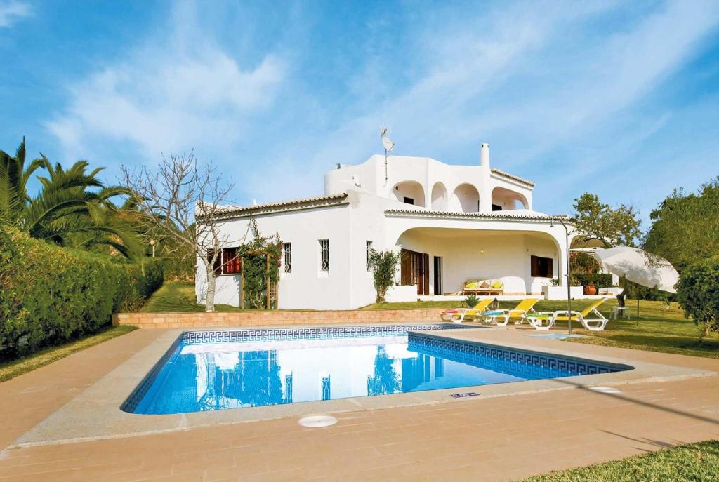 a villa with a swimming pool in front of a house at Casa do Alvor in Alvor