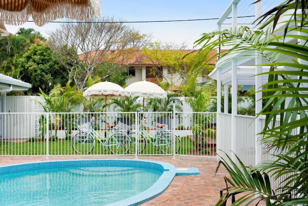 a swimming pool in front of a fence with umbrellas at Blue Heron Boutique Motel in Gold Coast