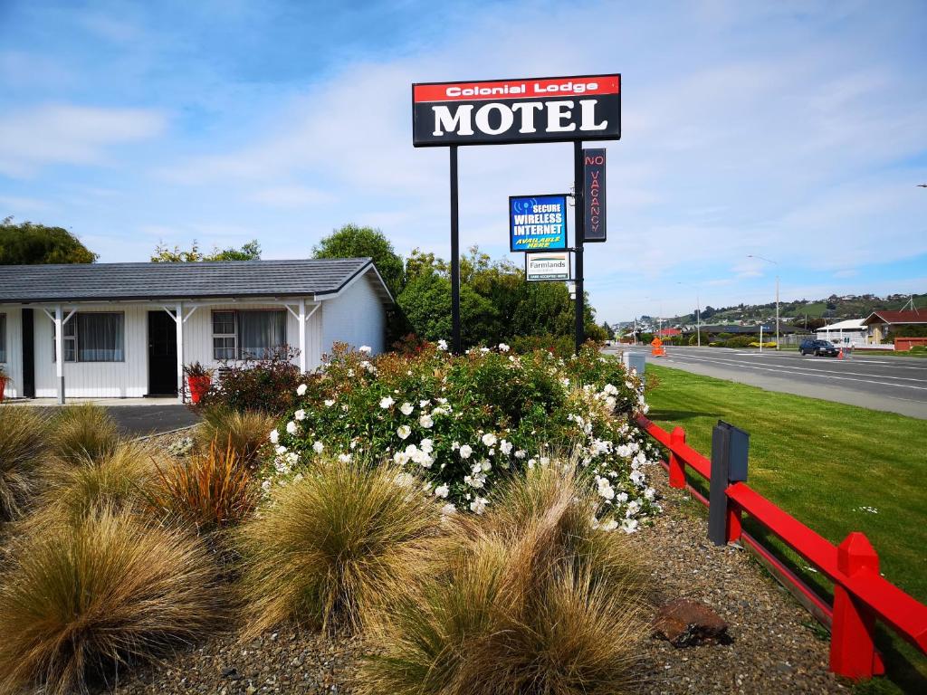 a motel sign in front of a field of flowers at Colonial Lodge Motel in Oamaru