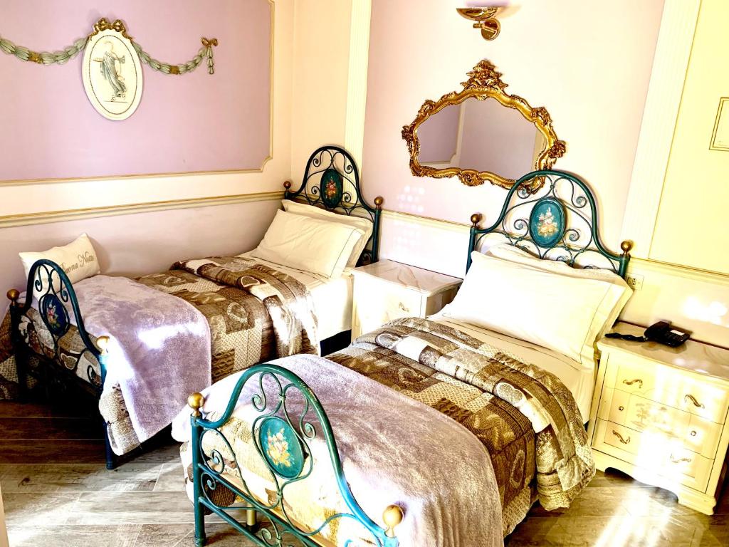 una camera con due letti e uno specchio di Hotel Vandelli a Pavullo nel Frignano