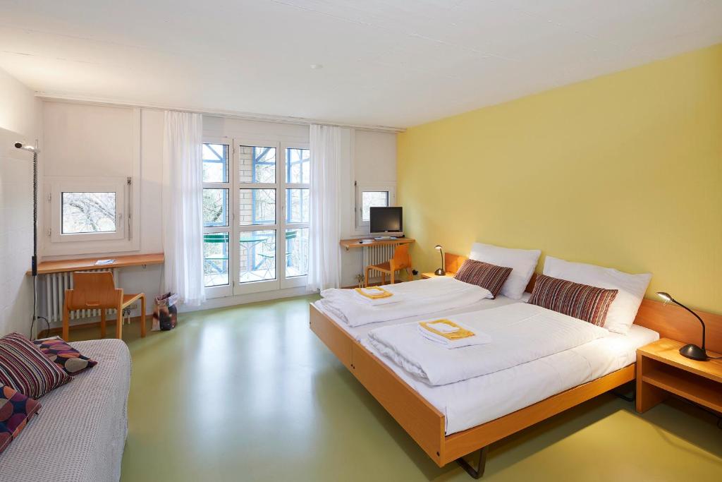 una camera con un grande letto bianco e un divano di Seminarhotel Romerohaus a Lucerna