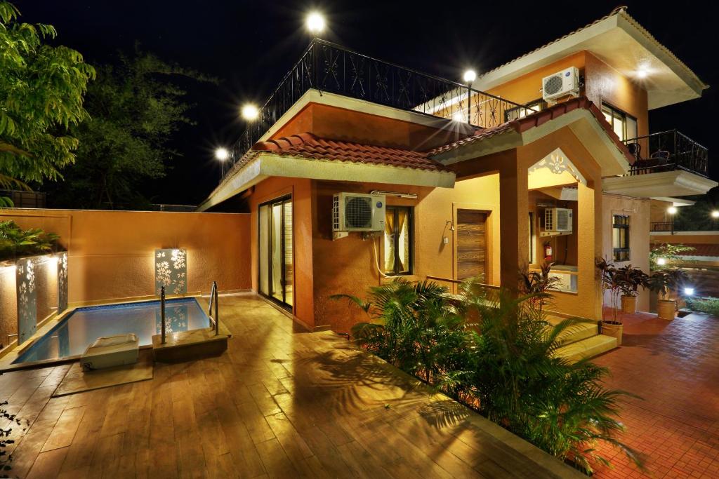 a house with a swimming pool at night at SaffronStays Nithyam, Vikramgad in Pālghar