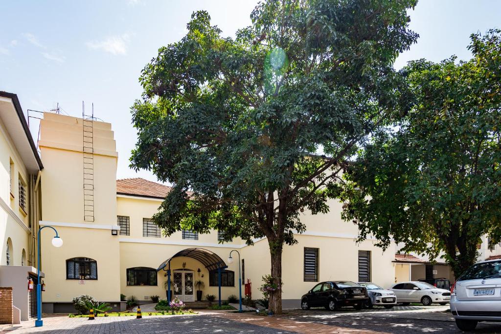 a building with cars parked in front of a tree at Eventos & Hospedagem Sagrada Família in Sao Paulo