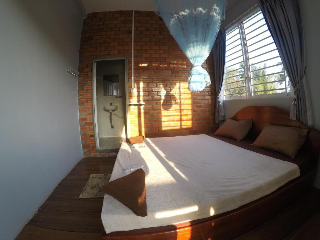 1 dormitorio con 1 cama grande en una pared de ladrillo en ING ING GUESTHOUSE en Koh Rong Sanloem