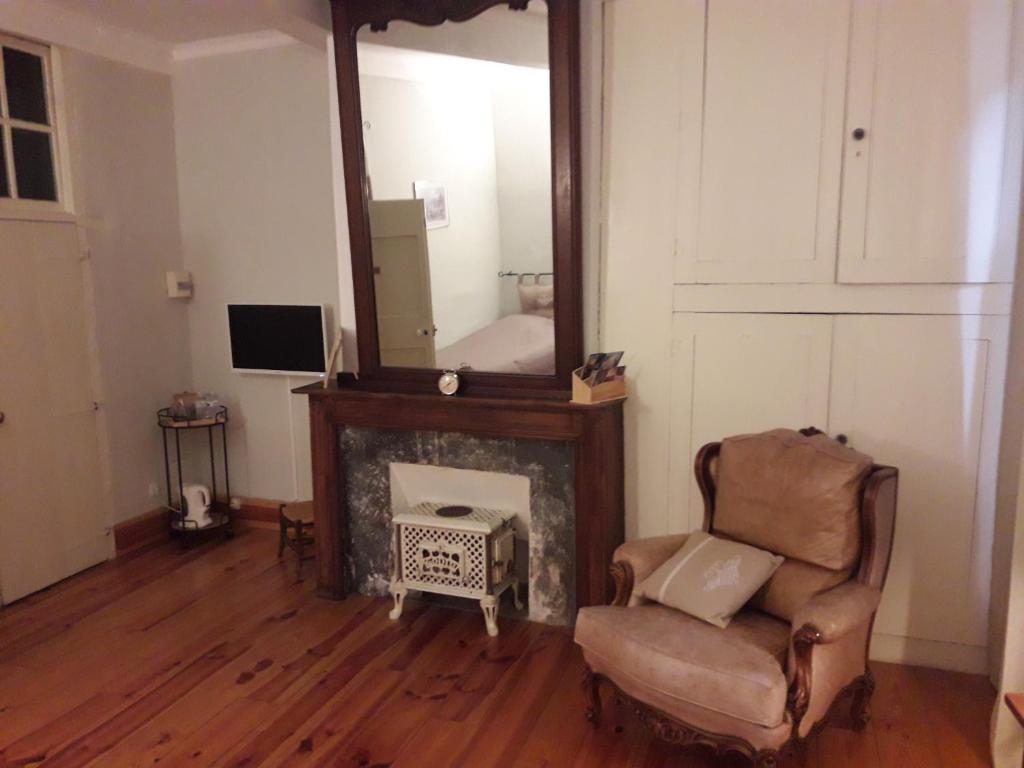 a living room with a mirror and a chair at Chambres d'hôtes Belle Occitane in Tarascon-sur-Ariège