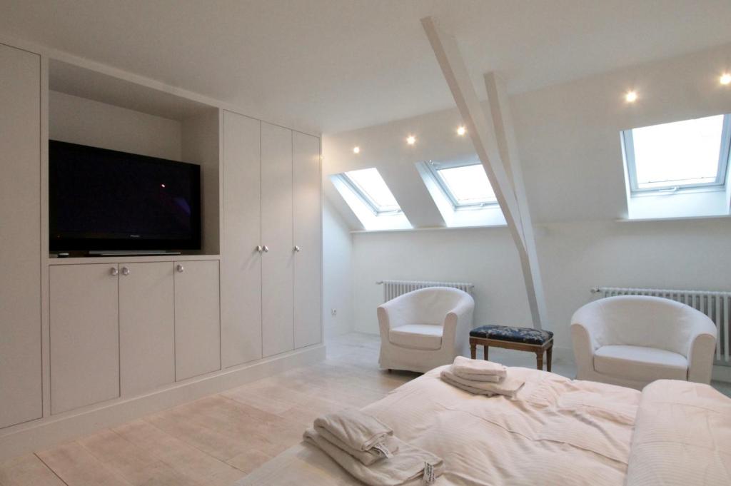 een slaapkamer met een bed en twee stoelen en een televisie bij Cap's House in Gent
