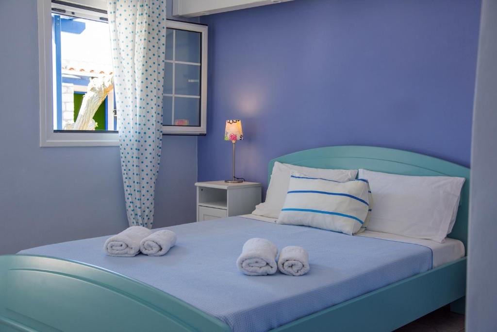 niebieska sypialnia z łóżkiem z ręcznikami w obiekcie Vikentios Rooms w mieście Kithira