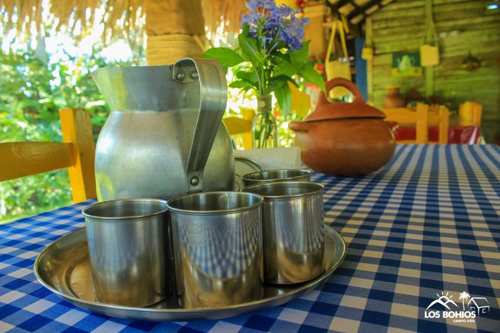 a tray with four cups on a table with a juicer at Los Bohios Campo Añil in Jarabacoa