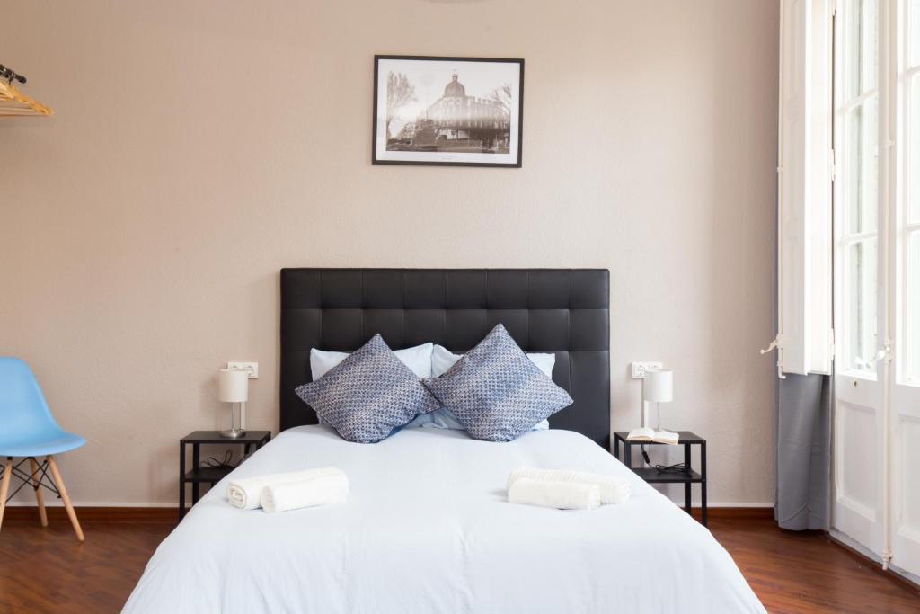 una camera da letto con un grande letto bianco con cuscini blu di Key Barcelona HOUSING (Carrer Girona) a Barcellona