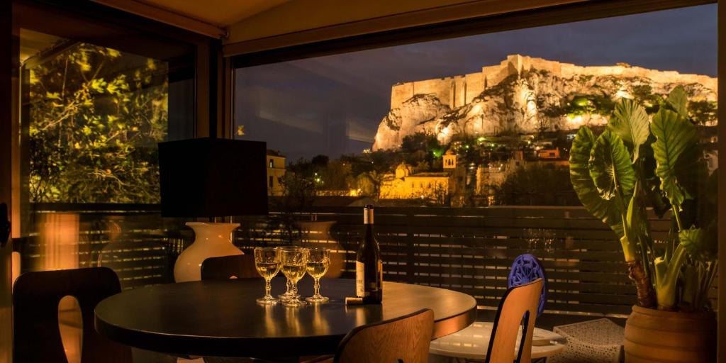 een tafel en stoelen met wijnglazen op een balkon bij Fos Residential Apartments in Athene