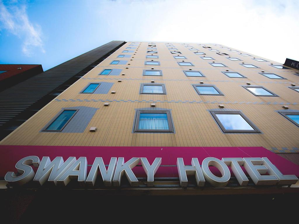 un edificio alto con un cartel delante en Swanky Hotel Otomo, en Sapporo