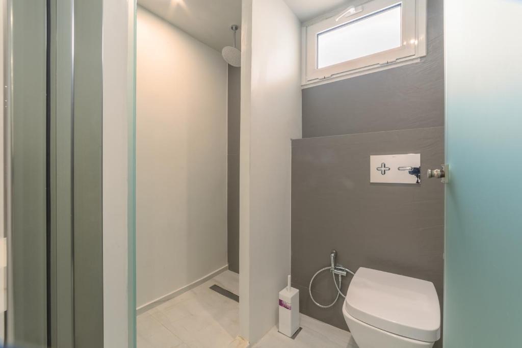 a bathroom with a toilet and a window at Atrion Resort Hotel in Agia Marina Nea Kydonias