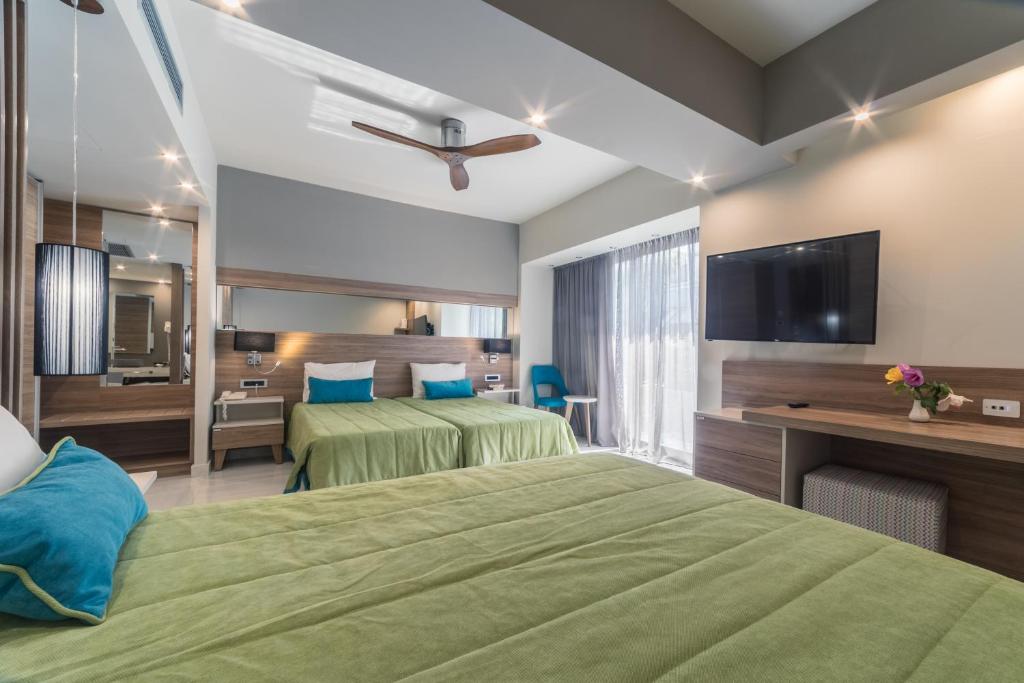 a hotel room with two beds and a flat screen tv at Atrion Resort Hotel in Agia Marina Nea Kydonias