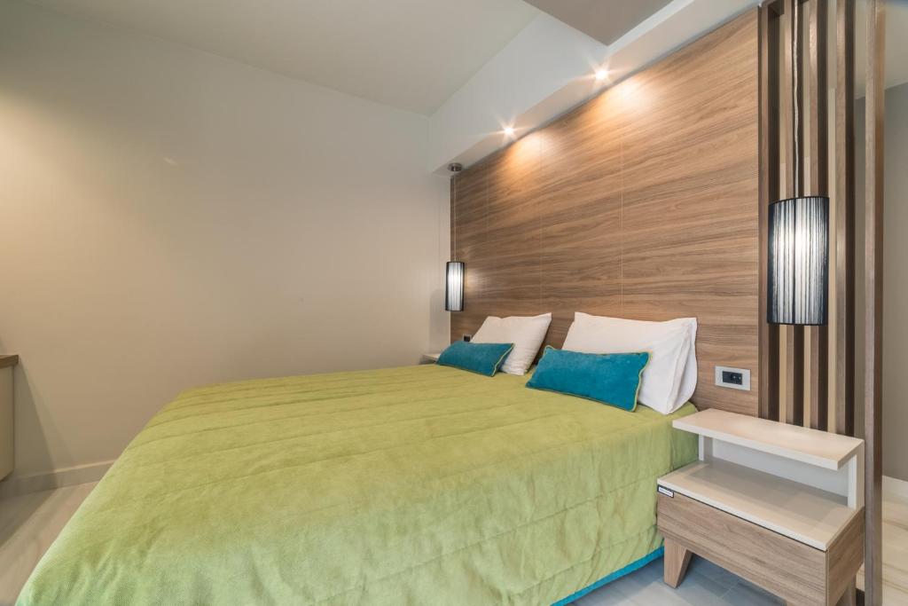 a bedroom with a green bed with a wooden headboard at Atrion Resort Hotel in Agia Marina Nea Kydonias