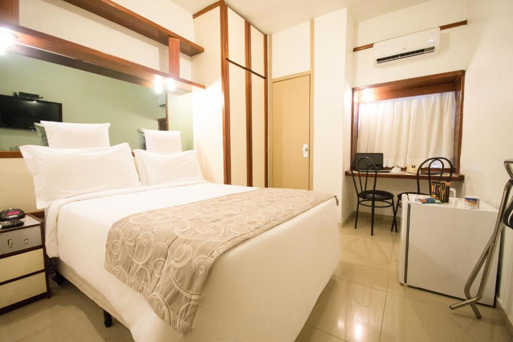 a bedroom with a large white bed and a desk at Royal Center Hotel Lourdes in Belo Horizonte