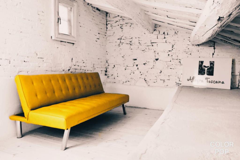 a yellow bench in a room with a white wall at Allegra Toscana - Affittacamere Guest house in Arezzo
