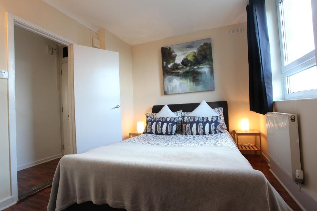um quarto com uma cama com almofadas azuis e uma janela em Chelsea off Kings Road One Bedroom Apartment with balcony em Londres