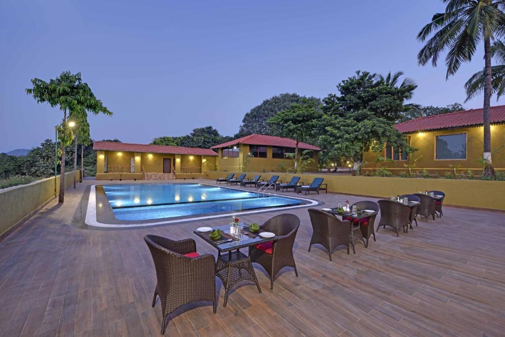 a patio with tables and chairs next to a swimming pool at Gir Lion Safari Camp by Trulyy, Sasan Gir in Sodaori