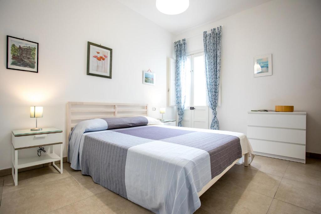 a white bedroom with a large bed and a window at Sunset Holiday House in Torre Lapillo