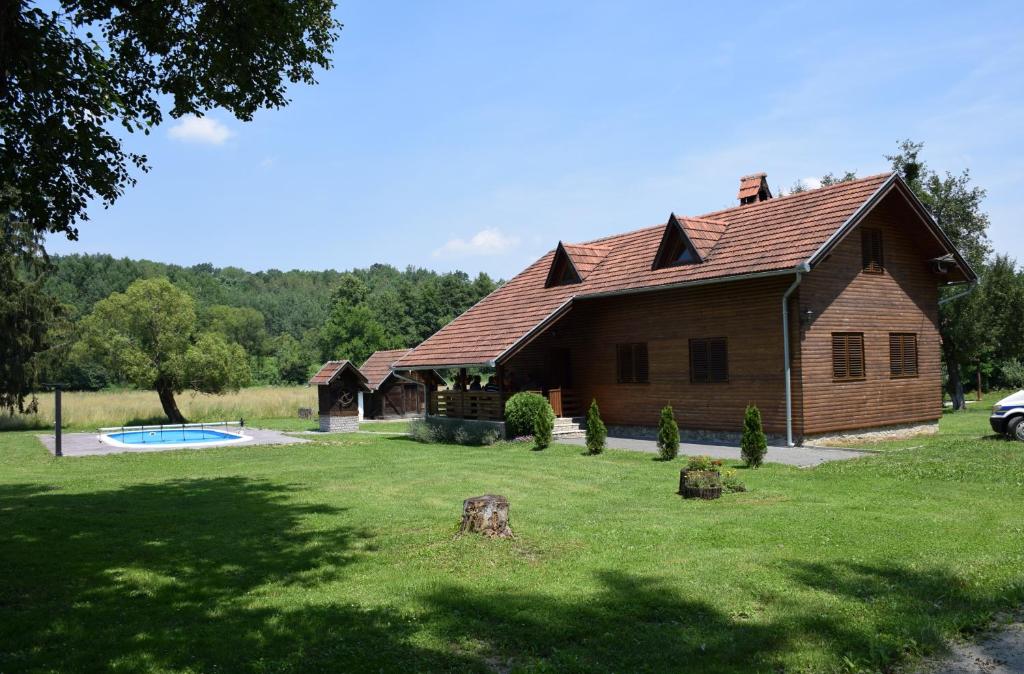 una casa di tronchi con piscina nel cortile di KRAJNA KUĆA ZA ODMOR a Čačinci