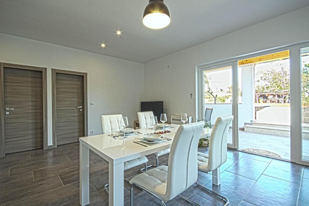 uma sala de jantar com uma mesa branca e cadeiras brancas em Apartman Topolino em Vodnjan