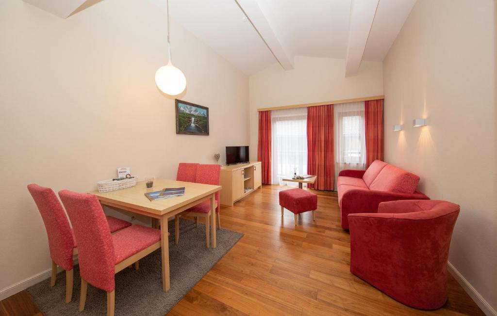 ein Wohnzimmer mit einem Tisch und roten Stühlen in der Unterkunft Arabella Golf- und Ski-Appartement in Zell am See