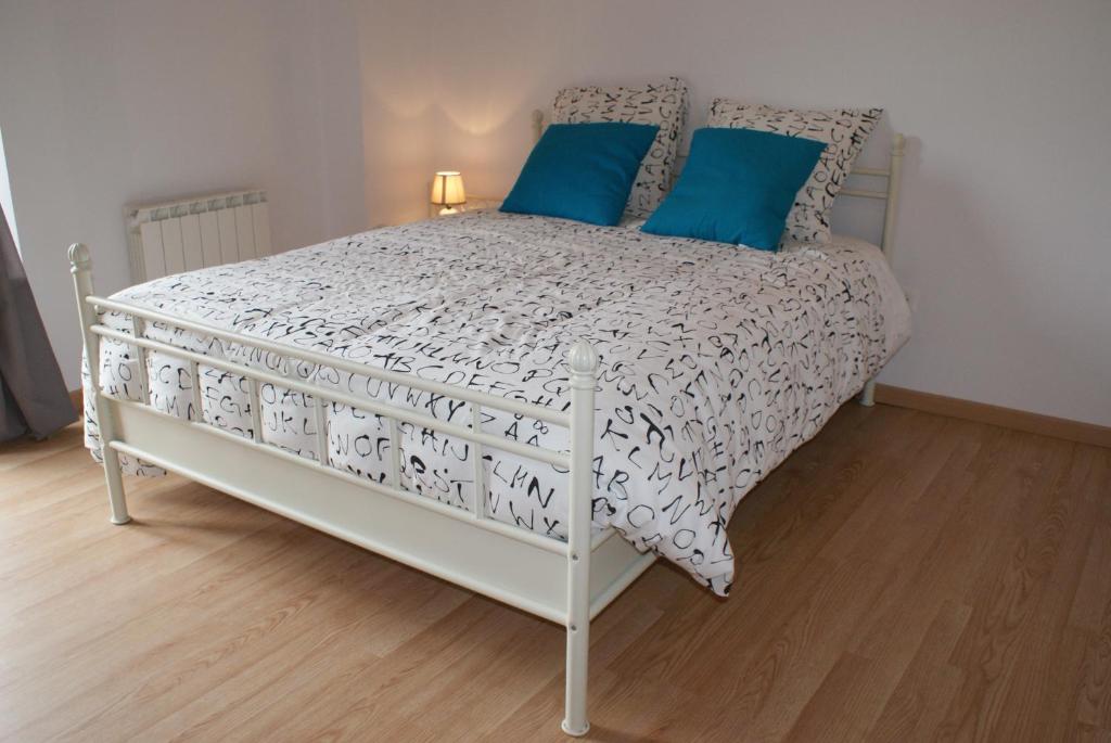 1 dormitorio con cama blanca y almohadas azules en Crezilles Hôtes en Crézilles