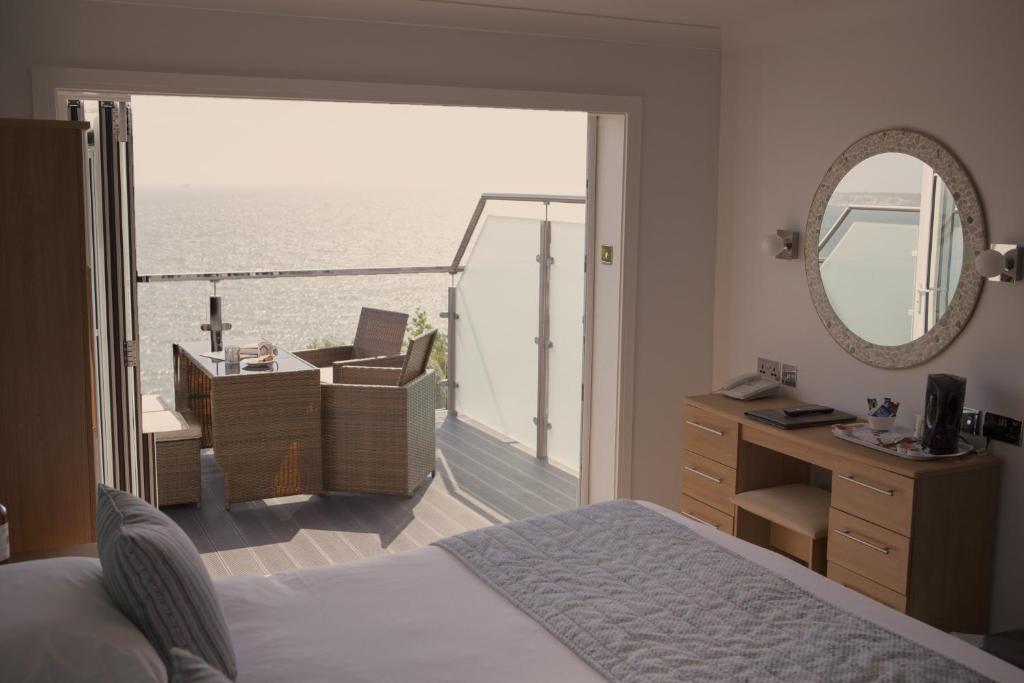 a bedroom with a bed and a view of the ocean at Luccombe Hall Hotel in Shanklin