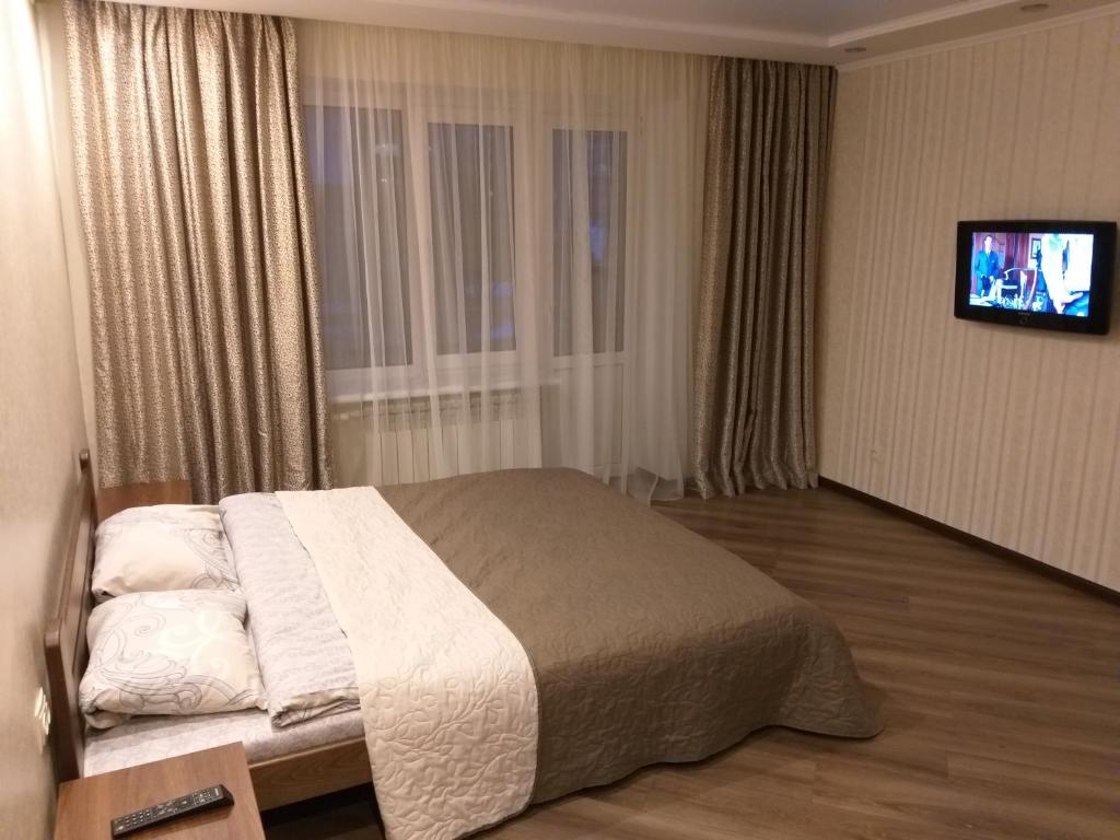 a bedroom with a bed with a tv on the wall at Затишна квартира в центрі in Vinnytsya