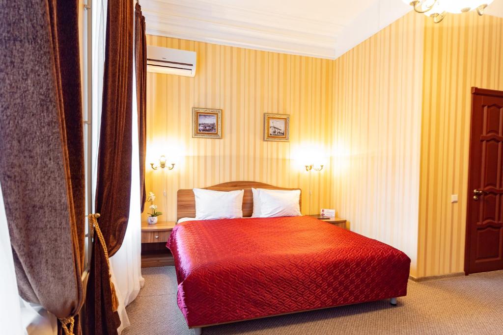 Habitación de hotel con cama roja y paredes amarillas en Na Dvoryanskoy Hotel, en Samara
