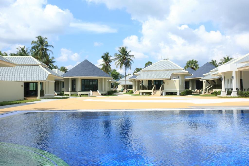 a villa with a swimming pool in front of houses at Wis Beach Khanom in Khanom