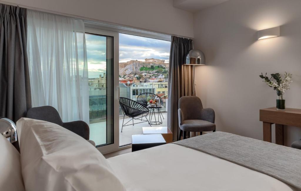 um quarto de hotel com uma cama e uma varanda em Elia Ermou Athens Hotel em Atenas